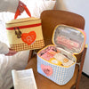 A yellow insulated lunch bag with a checkered pattern and a heart-shaped cartoon design is shown open on a wooden table.