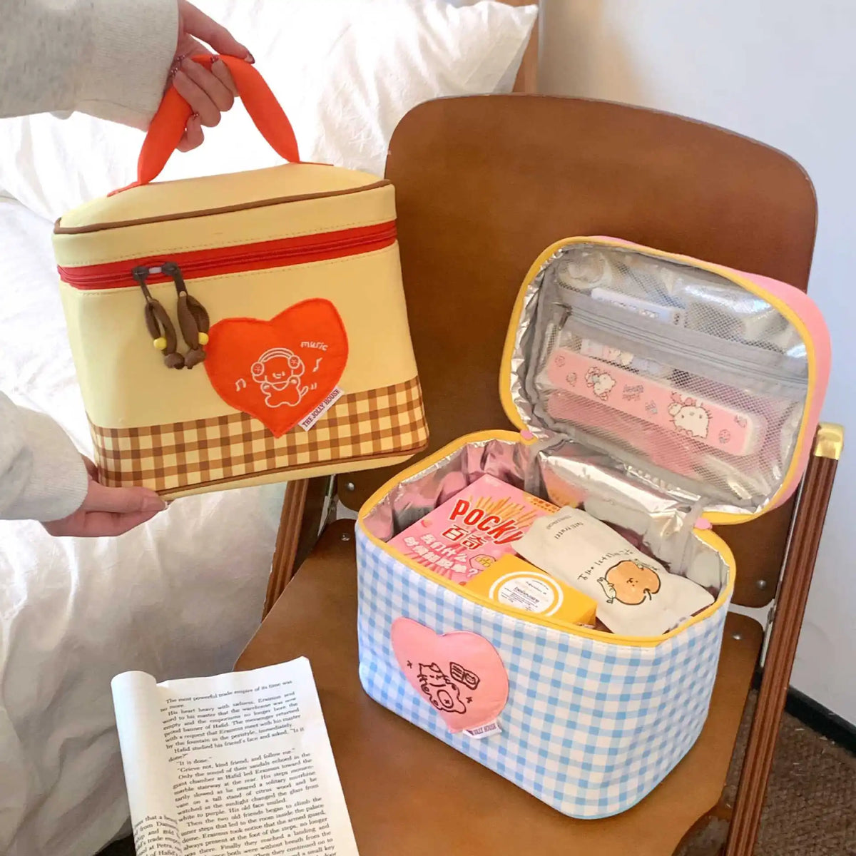 A yellow insulated lunch bag with a checkered pattern and a heart-shaped cartoon design is shown open on a wooden table.