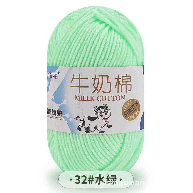 A ball of light green milk cotton blend yarn with a label indicating stretch properties.