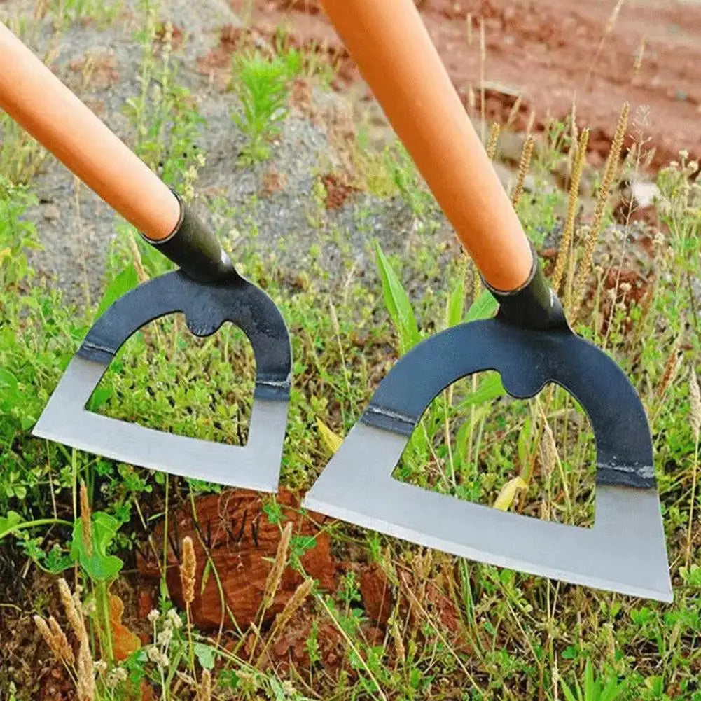A pair of black and silver handheld weeding rakes with orange handles resting in green grass.