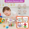 A baby is interacting with a sensory bin containing colorful shapes and toys, demonstrating hands-on learning.