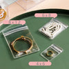Clear self-sealing jewelry storage bags with various sizes like 6x8, 8x12, and 4x6 displayed on a green surface.