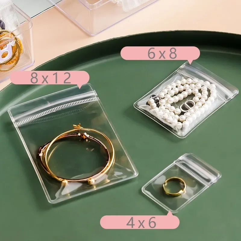 Clear self-sealing jewelry storage bags with various sizes like 6x8, 8x12, and 4x6 displayed on a green surface.