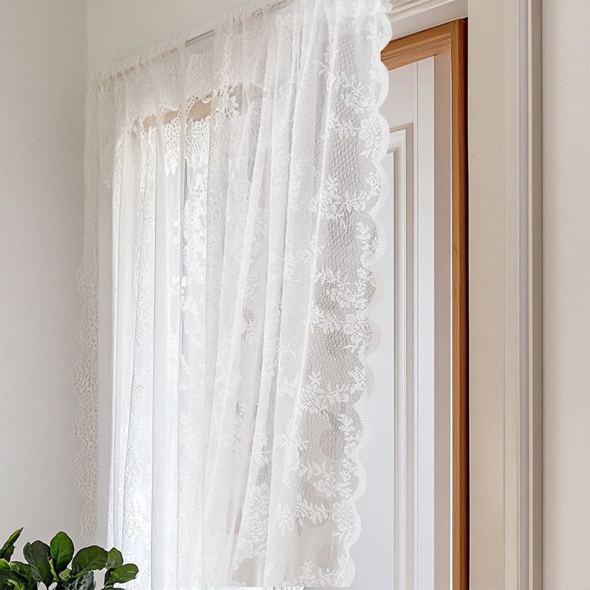 White sheer lace curtains hanging in a wooden frame on a light-colored wall.