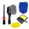 A set of car cleaning brushes including a black brush, a blue scrubbing brush, and yellow cleaning towels.