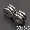 A close-up view of countersunk neodymium disc magnets with a center hole, showing stacked silver and black rings.