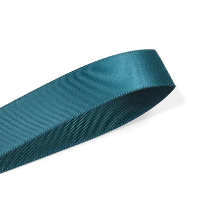 A dark teal double face satin ribbon roll is shown diagonally against a white background.