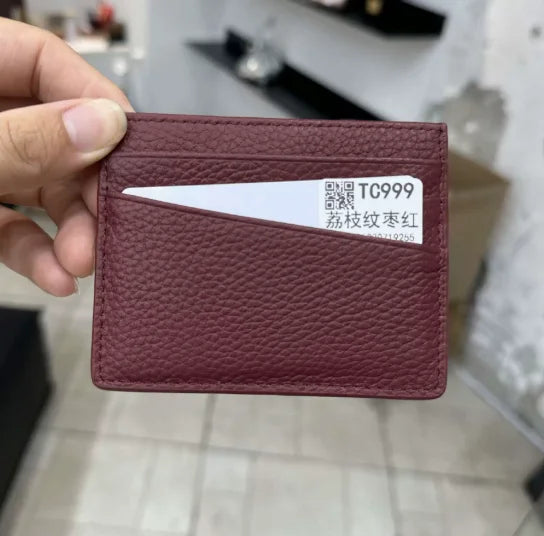 A maroon genuine leather slim card holder wallet with a white card inserted.