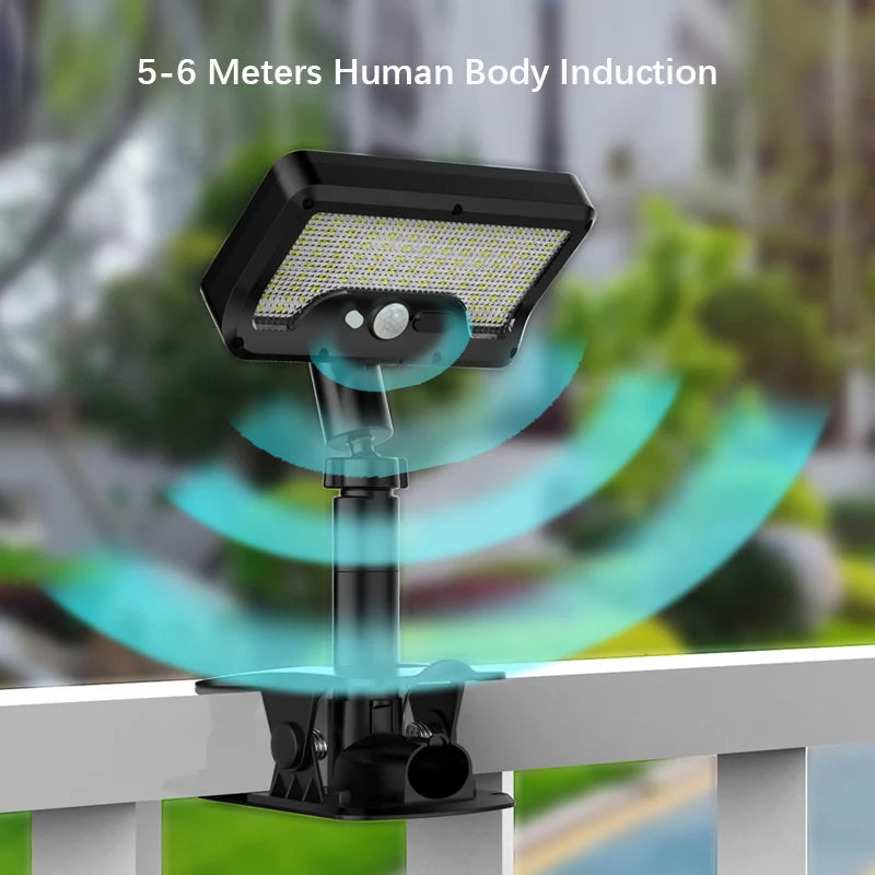 A black solar-powered motion sensor outdoor light fixture mounted on a railing.