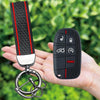 A black silicone key fob cover with a textured grip and panic button is shown being held in a hand.