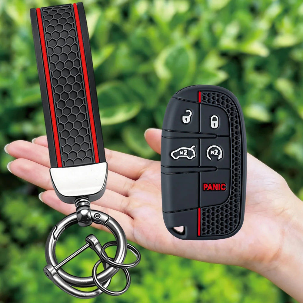 A black silicone key fob cover with a textured grip and panic button is shown being held in a hand.