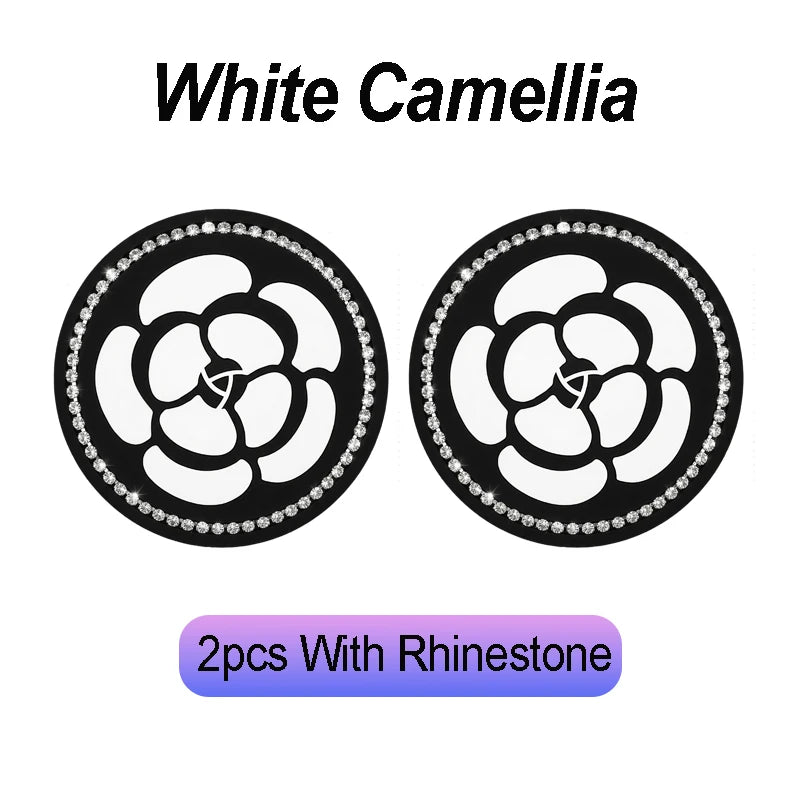 Two black non-slip coasters featuring a white camellia flower pattern and rhinestone accents.