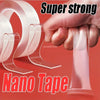 A hand is holding a piece of clear pink nano tape, with other rolls of the same tape visible in the background.