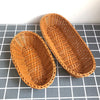 A pair of woven wicker serving baskets in a natural tan color resting on a gray grid surface.