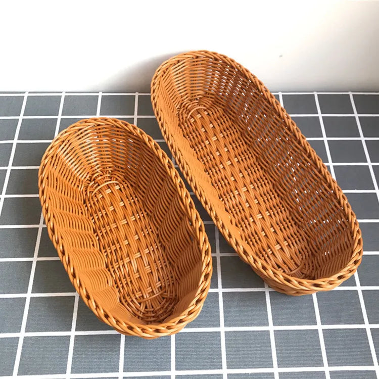 A pair of woven wicker serving baskets in a natural tan color resting on a gray grid surface.