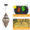 A decorative solar hollow-out lantern with a patterned glass shade, shown next to its charging panel and illuminating a wall 