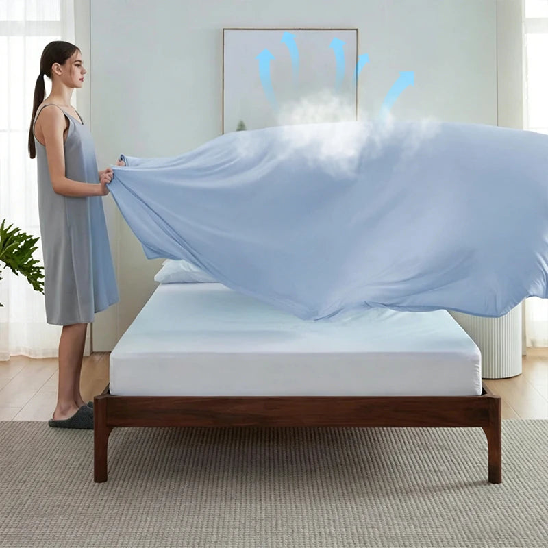A light blue ice silk blanket is draped over a bed in a bright room.