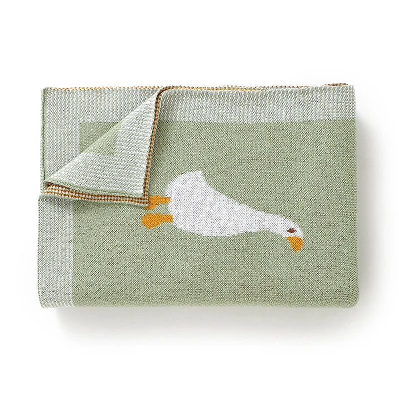 A soft cotton baby swaddle blanket in sage green with a white cartoon chicken print.