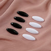 A set of eight oval scarf pins in black and white are displayed on a pink fabric background.