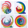 A set of wooden rainbow stacking blocks in various colors arranged in a spiral formation.