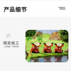 A set of three adorable resin Highland cow figurines in vibrant orange and brown colors displayed on green grass.