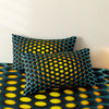 A close-up of a teal and black geometric duvet cover set featuring a pattern of yellow circles on a bed.