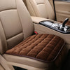 A brown quilted seat cover protector is placed on a beige car seat, showing the interior upholstery and door panel.