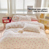 A pink duvet cover set with a white background and small pink bows is displayed on a bed, next to a window.