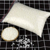 A white bag of natural soy wax granules next to a small bowl of the same granular material on a black grid surface.
