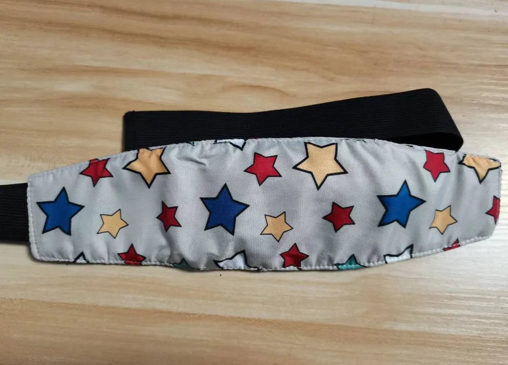 A gray fabric sleeping headrest for a baby car seat featuring colorful star shapes and a black adjustable belt strap.