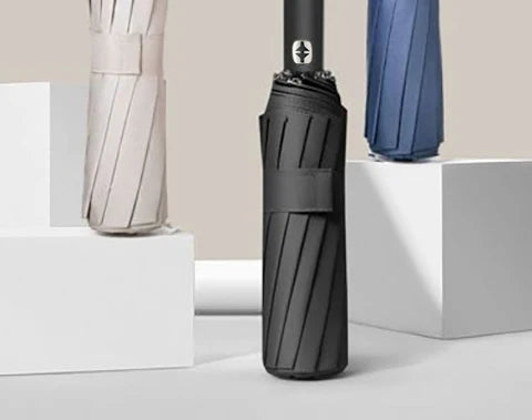 A black automatic compact folding umbrella is shown next to a beige umbrella.