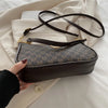 A dark brown PU leather crossbody bag with a gold accent chain is shown resting on a white fabric background.