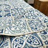 A blue and white patchwork cotton bedspread with a quilted pattern is displayed on a surface.