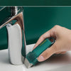 A hand is using a teal eraser to clean limescale from a chrome faucet.