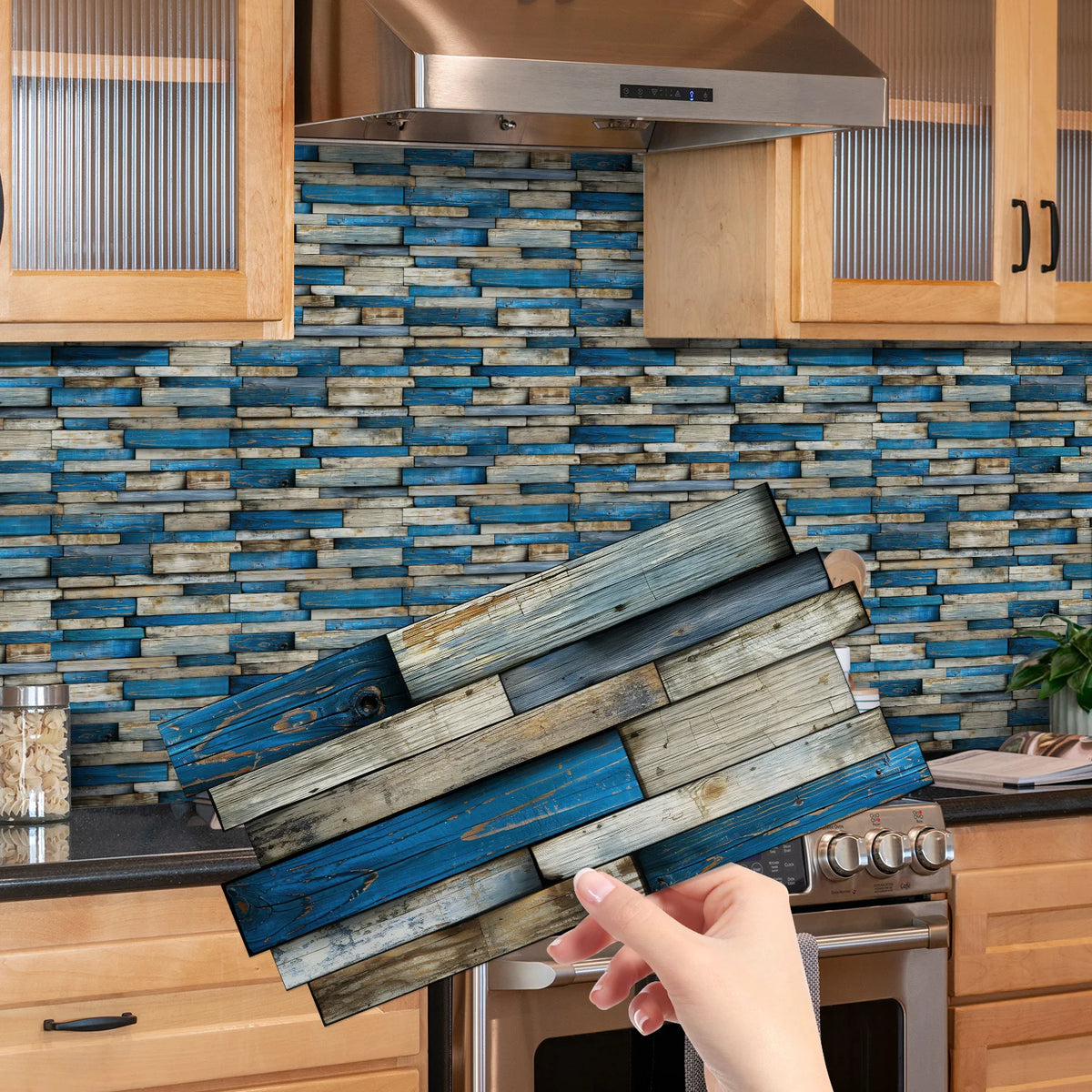 A hand is peeling off blue and gray wood tile stickers from a kitchen backsplash.