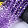 Purple faceted crystal glass spacer beads strung together on a black background