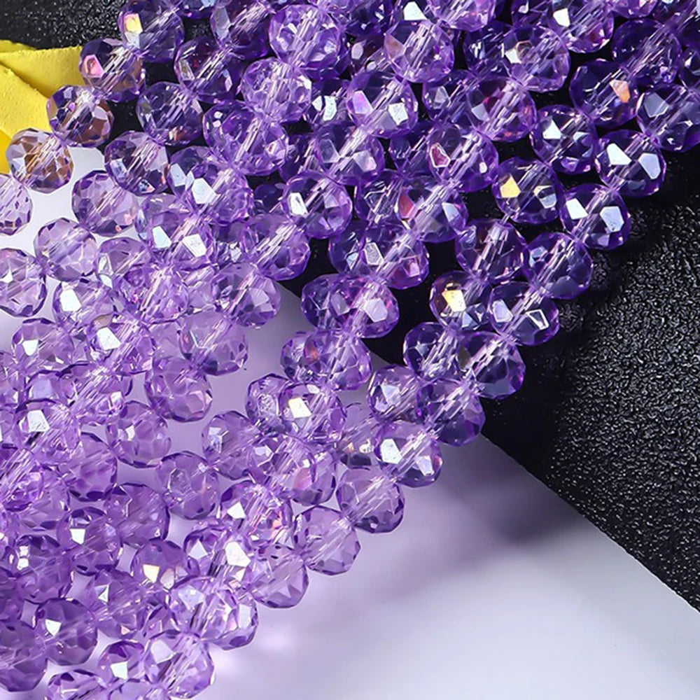 Purple faceted crystal glass spacer beads strung together on a black background