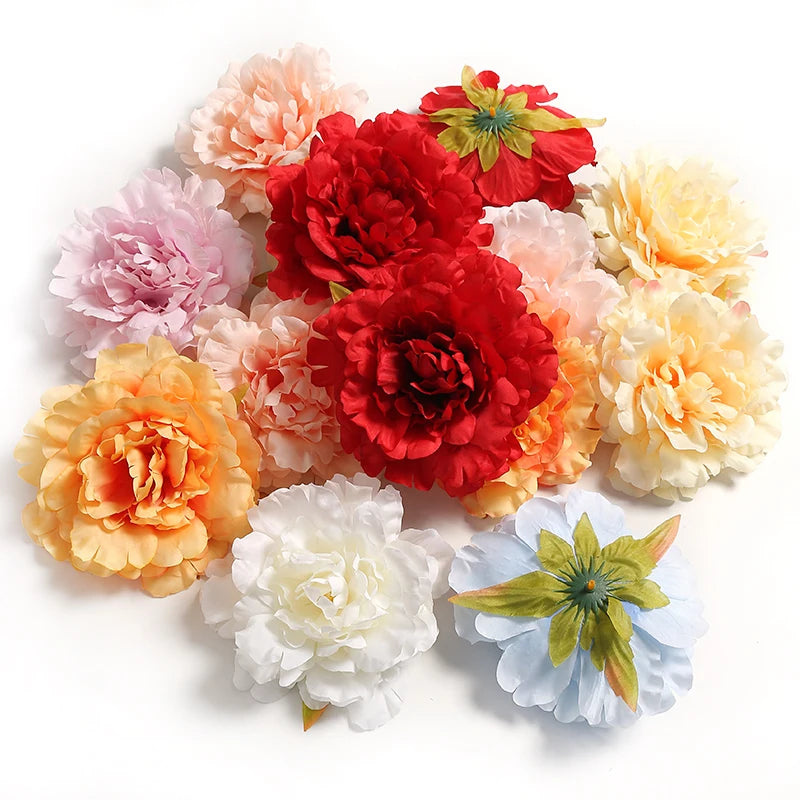 A cluster of lifelike silk peony flower heads in shades of pink, orange, and red.