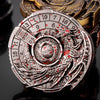 A silver metal spinner dice cube featuring a dragon design and numbered faces, set in a dark background.