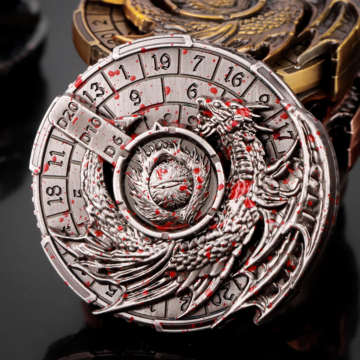 A silver metal spinner dice cube featuring a dragon design and numbered faces, set in a dark background.