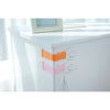 Close-up of white cabinet doors showing orange and pink adhesive baby proofing latches.