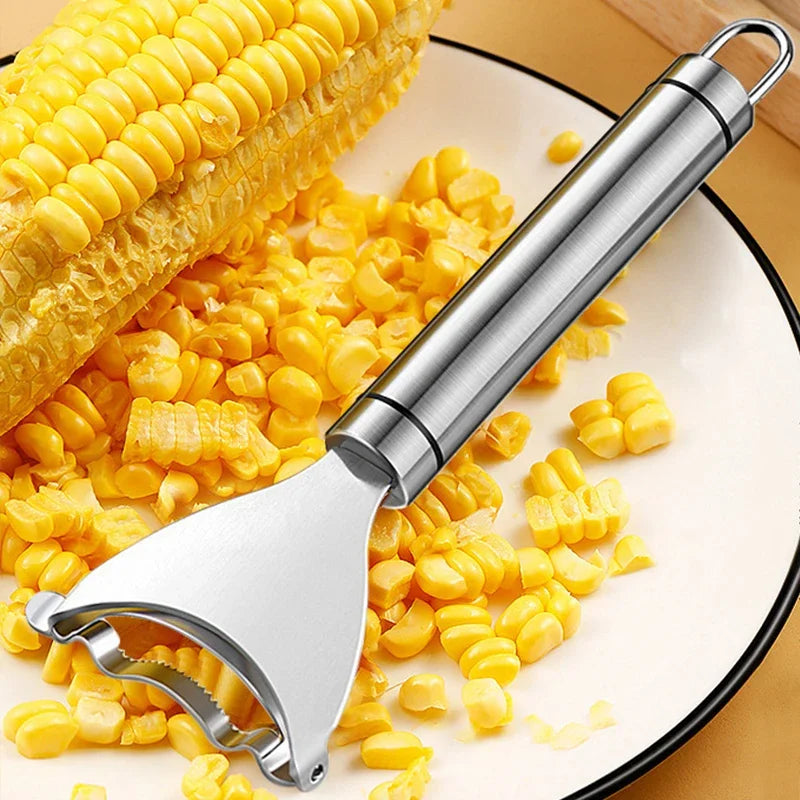 A stainless steel corn peeler is shown next to kernels of corn and a corn cob.
