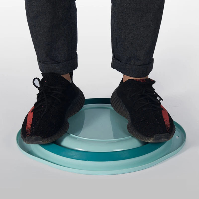 A pair of legs and feet wearing black pants and black shoes standing over a light blue wash basin.
