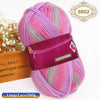 A skein of gradient pink and gray wool blend yarn is shown next to a wooden box.