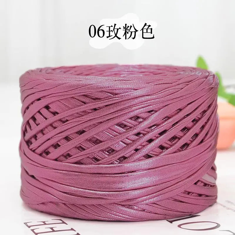A spool of metallic pink flat ribbon yarn for crochet and knitting
