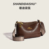 A brown PU leather crossbody shoulder bag with gold hardware and patterned strap.