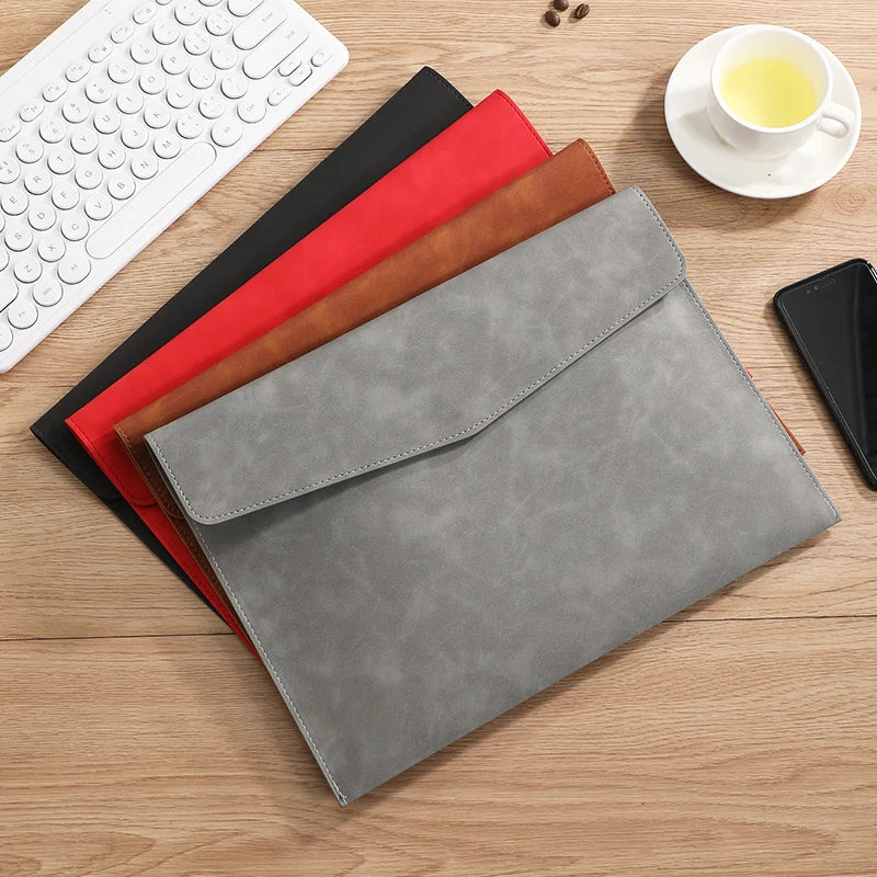 Une pile d'organisateurs de documents A4 en cuir PU haut de gamme, rouges, noirs et beige, à côté d'un clavier blanc et d'une