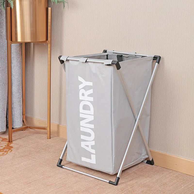 A large gray foldable laundry basket with a mesh top is displayed next to a wooden stand.