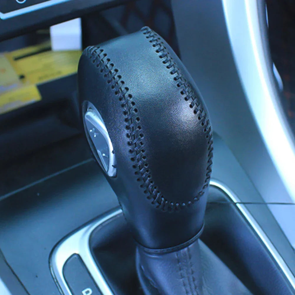 Close-up of a black gear shift knob cover with stitching on a vehicle transmission.