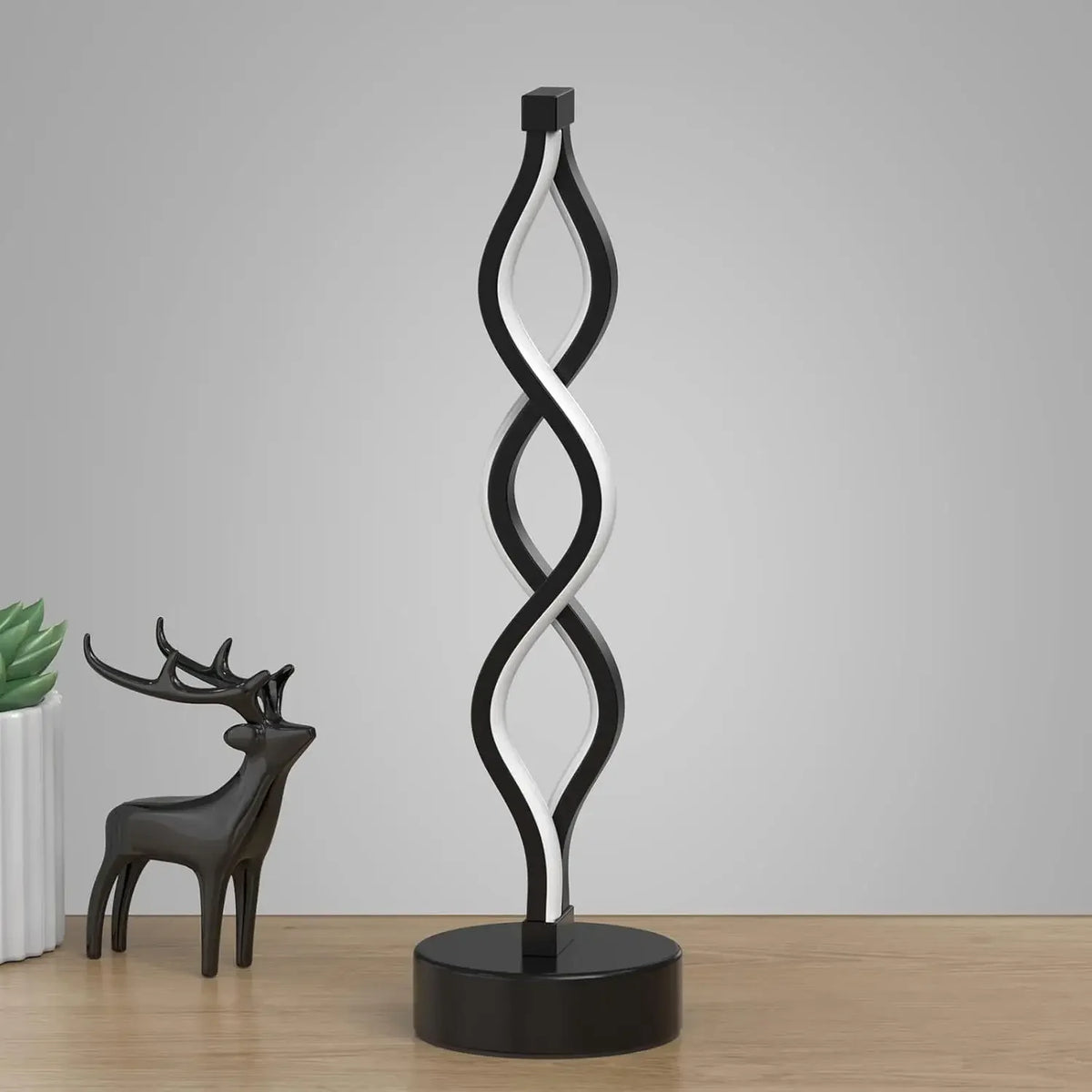 A black and white, twisted seaweed-shaped desk lamp with a dark base.
